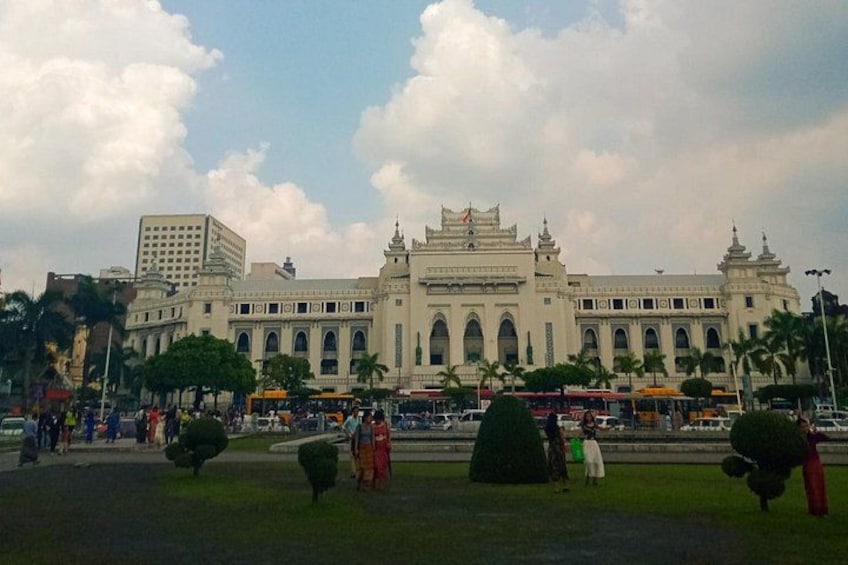 A large, ornate building with multiple arches and a central tower, surrounded by palm trees and a busy street with buses. 1