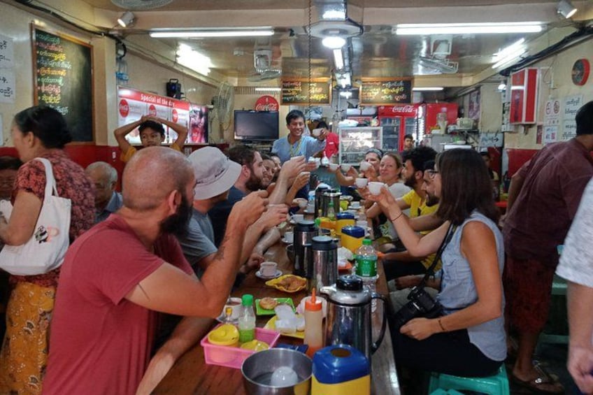 A crowded food court with people eating and standing around. 2