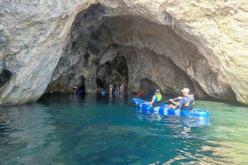 People kayaking in a cave with clear water. 2