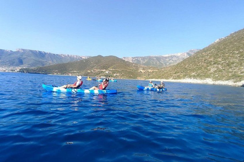 People kayaking on a calm lake with mountains in the background. 3