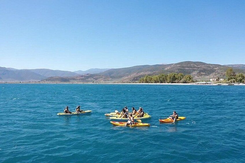 People kayaking on a calm sea with mountains in the background. 3