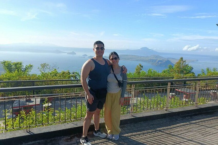 A couple standing on a balcony with a scenic view of mountains and a body of water. 4