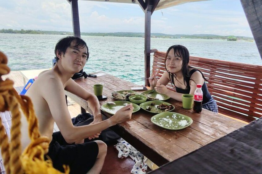 Two people dining on a boat with a view of the water and distant land. 2
