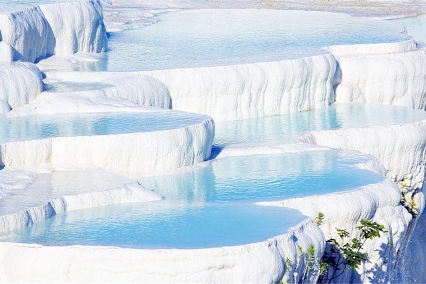 Terraced pools of clear water, surrounded by white mineral formations. 1