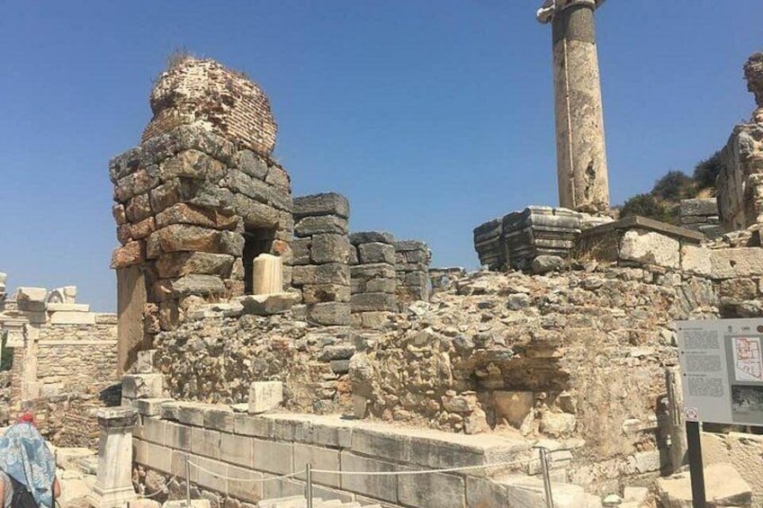 Ancient ruins with stone columns and a large stone structure. 2