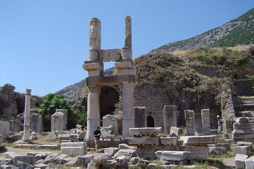 Ancient ruins with stone columns and arches, set against a hillside backdrop. 3