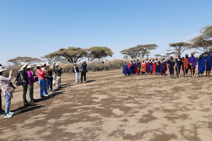 A group of people standing in a line outdoors with trees in the background. 5