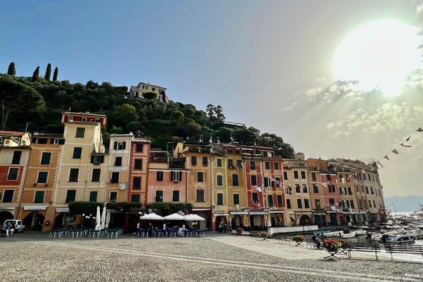 A coastal town with colorful buildings, a marina, and a hilltop structure. 2