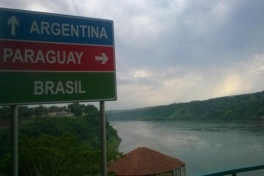 A river with a sign indicating directions to Argentina, Paraguay, and Brazil. 3