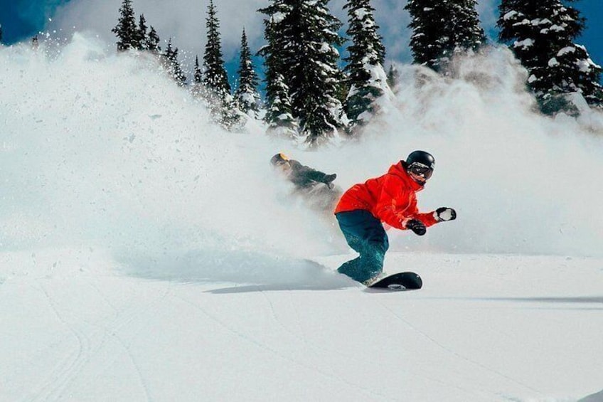 A person snowboarding down a snowy slope with trees in the background. 3