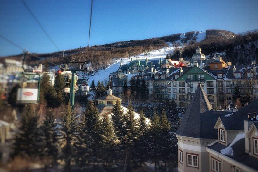A ski resort with buildings, a ski lift, and snow-covered slopes. 2