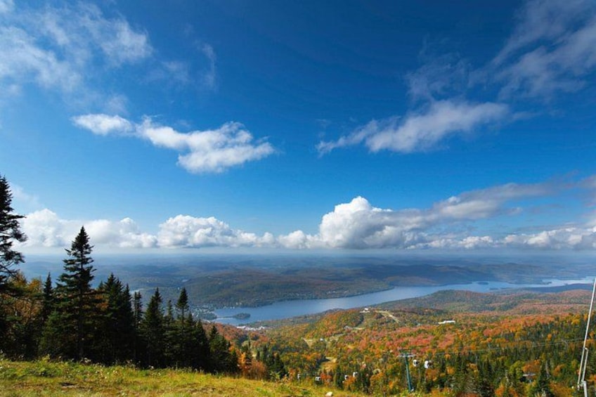 A mountainous landscape with a lake, autumn foliage, and a clear sky. 1