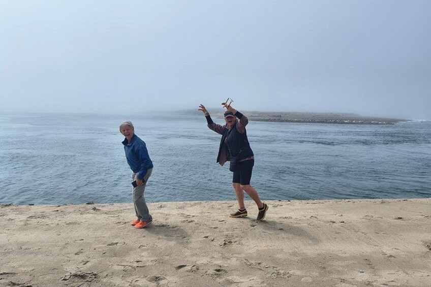 Two people standing on a sandy beach with the ocean in the background. 5