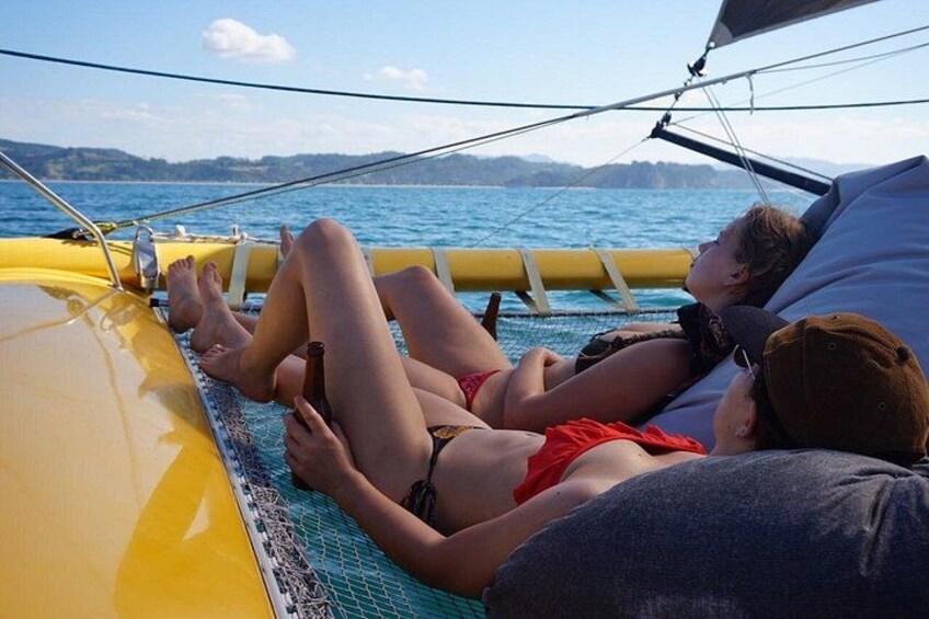 Personas relajándose en un barco con vistas al mar y colinas al fondo. 1