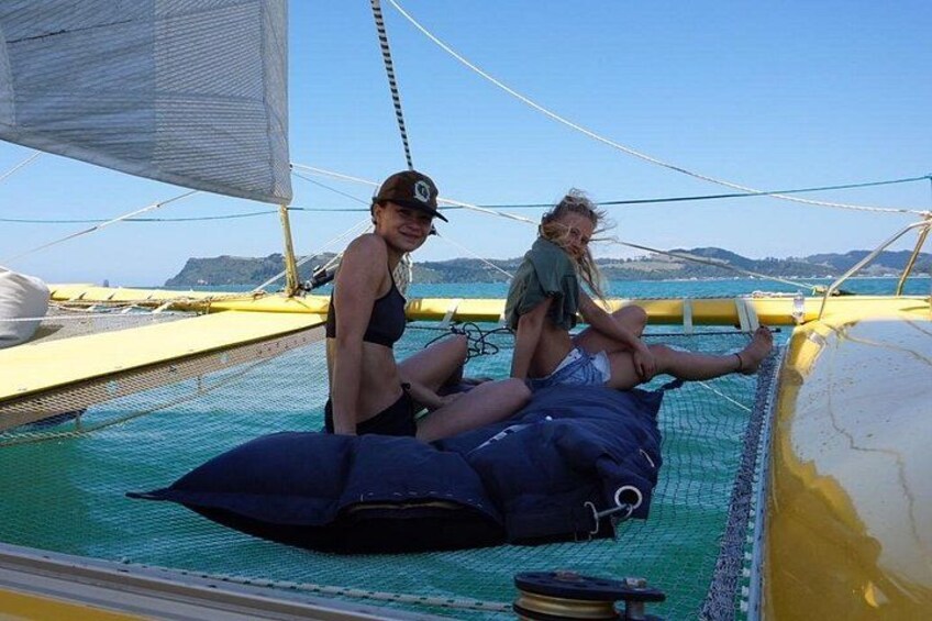 Two people on a sailboat with a clear sky and distant land in the background. 3