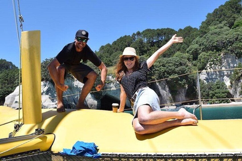 A person on a yellow boat, another person on a dock, and a rocky coastline with trees. 4