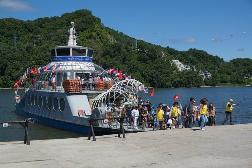A ferry docked at a pier with people boarding and disembarking. 3