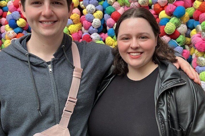 Two people standing in front of a wall of colorful balls. 5