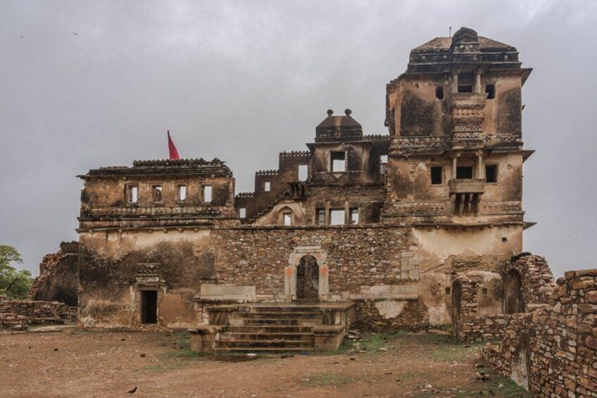 Un bâtiment ancien et délabré, surmonté d’un drapeau rouge, entouré de ruines. 2