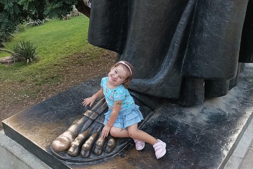 Un niño sentado sobre una escultura con una gran estructura negra al fondo. 4
