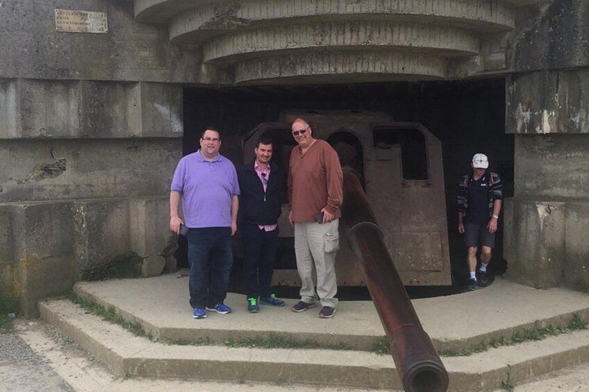 A group of people standing in front of a large cannon, with a building entrance in the background. 2