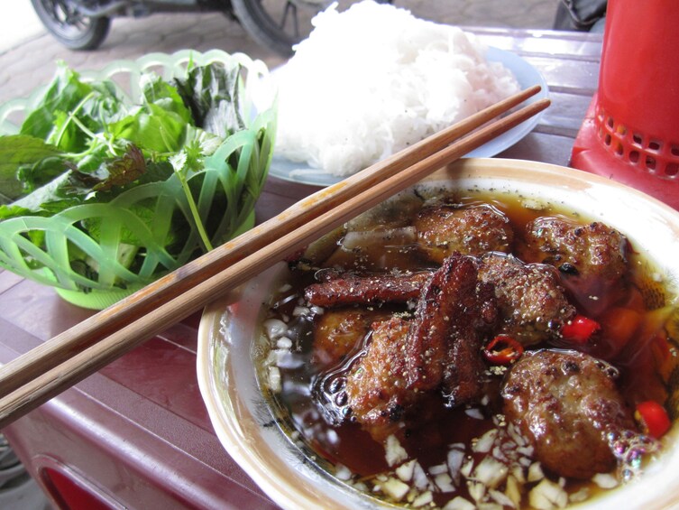 A bowl of meatballs in a dark sauce, a plate of white rice, and a side of green leafy vegetables. 4