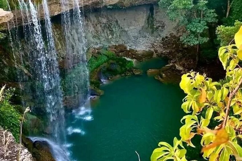 A waterfall cascading into a turquoise pool surrounded by greenery. 4