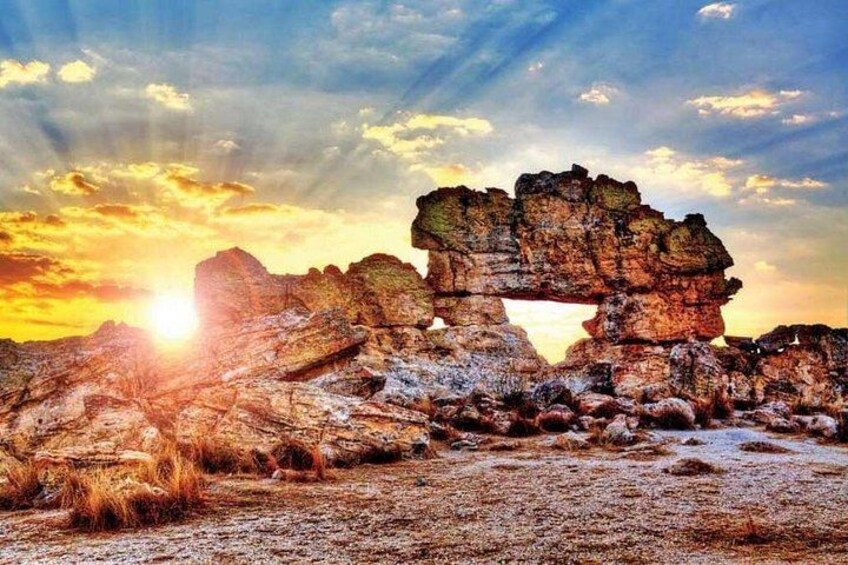 A rock formation with a natural arch at sunset. 1