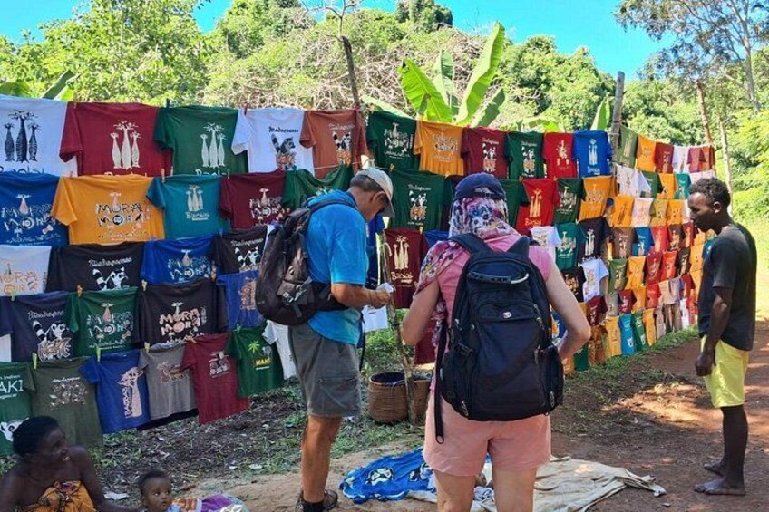 A group of people standing in front of a wall of colorful t-shirts. 2