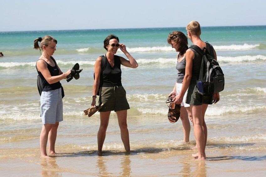 Three people standing on a beach with ocean waves in the background. 4