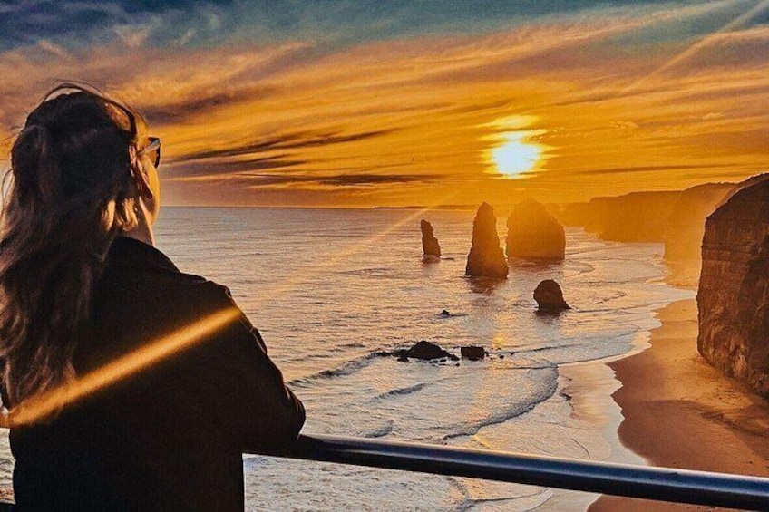 A person overlooking a coastal landscape with rock formations during sunset. 3