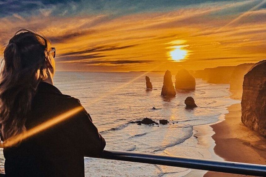 A person overlooking a coastal landscape with rock formations during sunset. 3