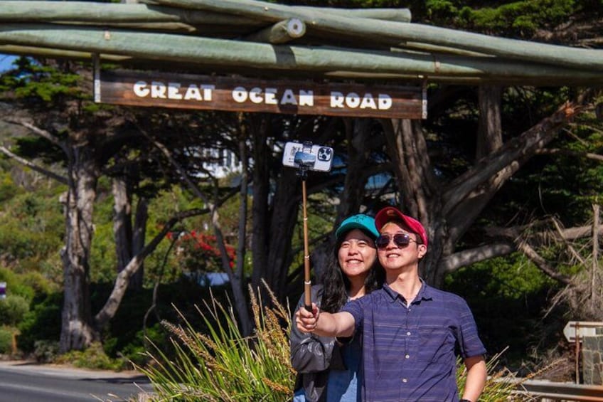 A couple taking a selfie with a sign that reads 'Great Ocean Road'. 2