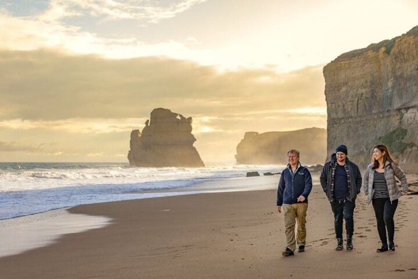 A beach with a large rock formation in the background, a sandy shore, and a calm sea. 2