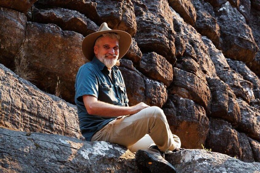 A person sitting on a rock with a dog. 2