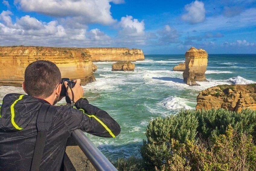 A person taking a photograph of coastal rock formations and the ocean. 3