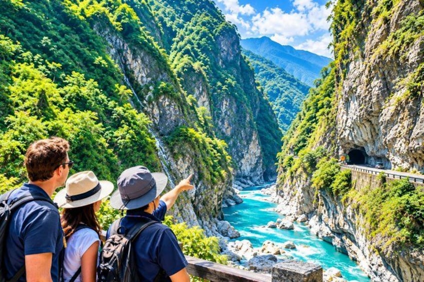 A family standing on a bridge overlooking a turquoise river with steep cliffs and lush greenery. 2