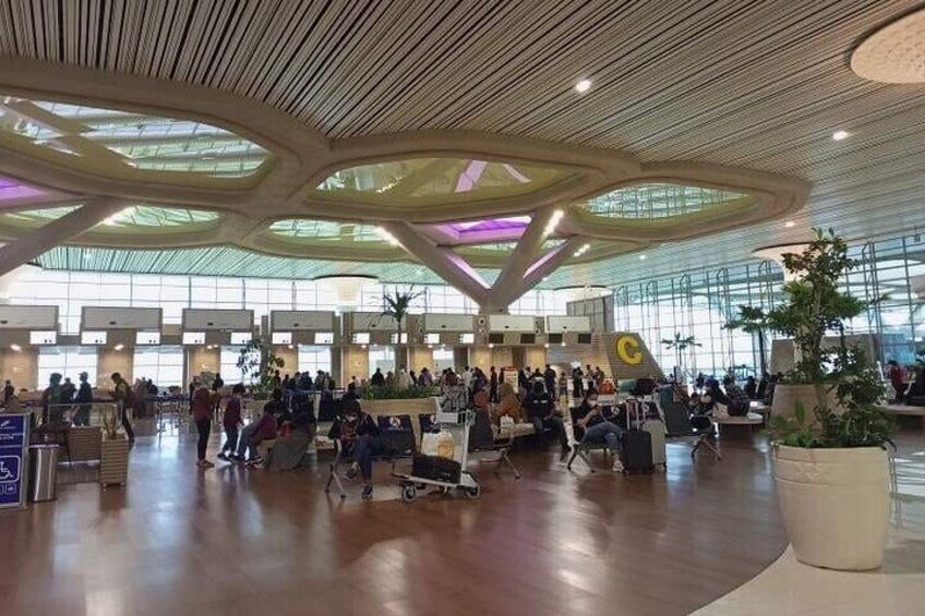 A spacious airport terminal with a modern ceiling design and a large seating area. 2