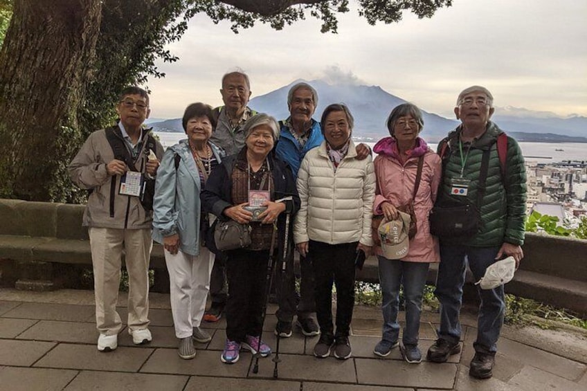 A group of people standing on a stone platform with a mountain and cityscape in the background. 4