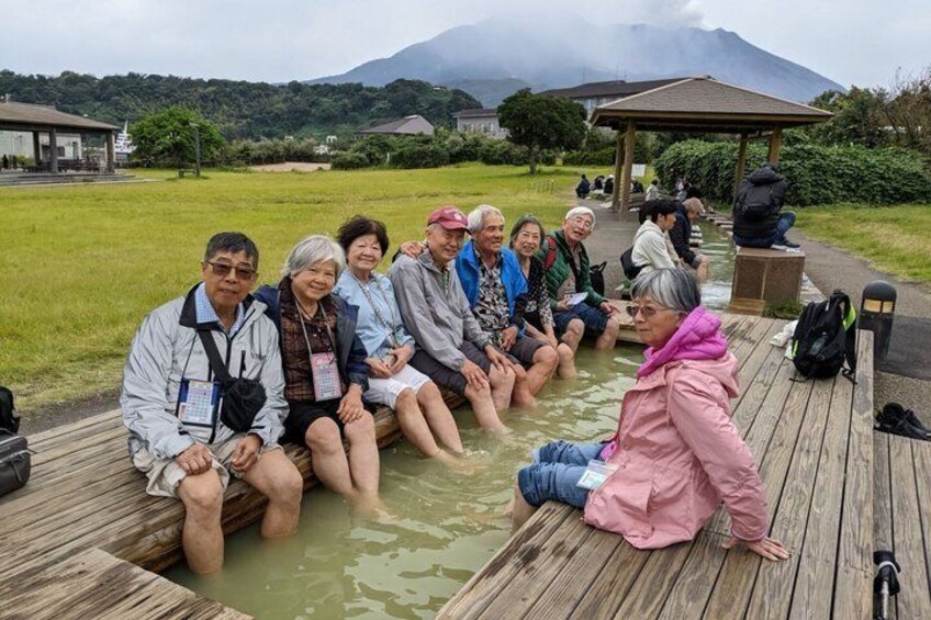 A group of people sitting on a wooden dock in a natural setting with a mountain in the background. 5