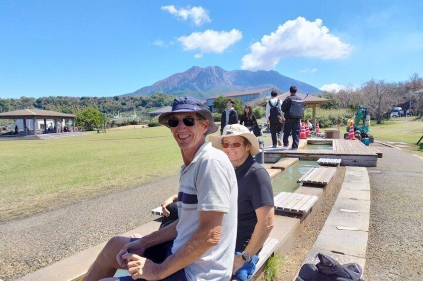 Two people sitting on a bench with a mountain in the background. 1