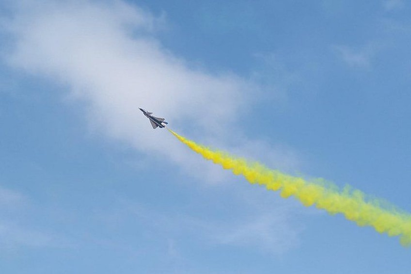 Un avion à réaction laissant derrière lui une traînée de fumée jaune sur un ciel bleu. 1