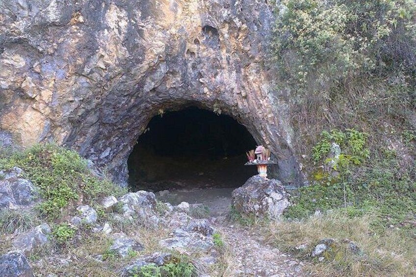 A cave entrance with a small shrine in front. 4