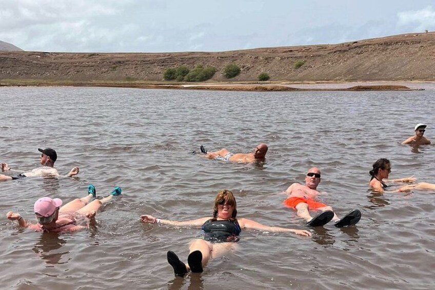 People floating on a body of water with a hilly landscape in the background. 1