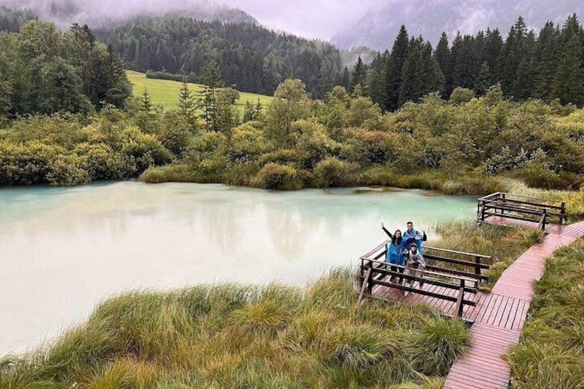A lake surrounded by forest, a wooden boardwalk, and people on the boardwalk. 2
