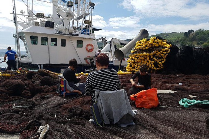 En båd, mennesker og fiskegrej på stranden. 4