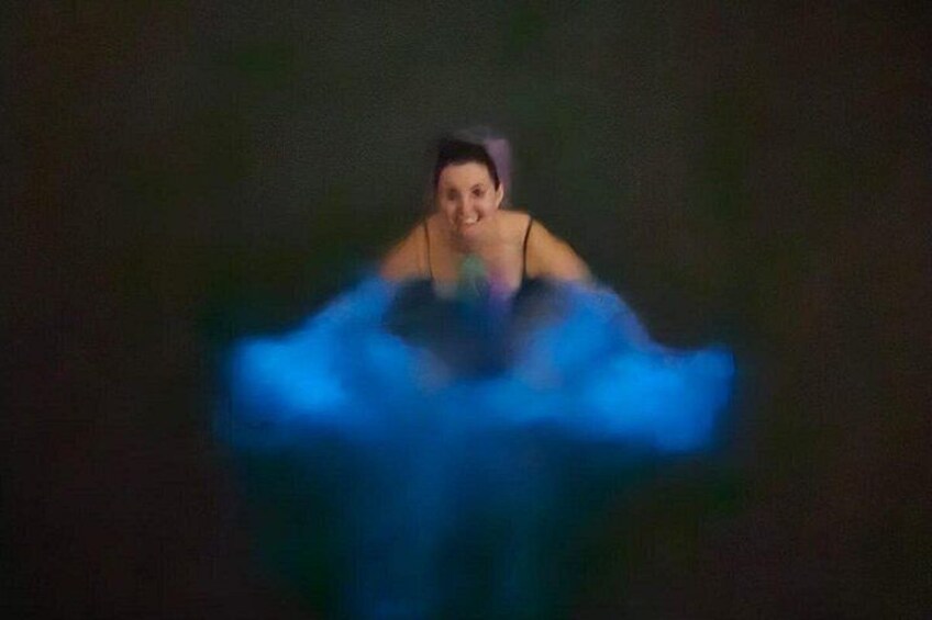 A person in a dark setting with a blurred blue object in the foreground. 4