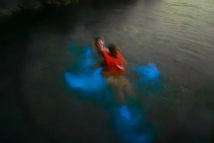 A person floating on a blue object in water. 2