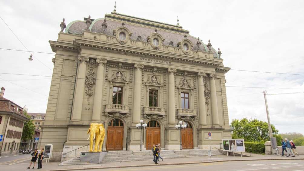 Un teatro imponente con arquitectura ornamentada y una estatua dorada de un elefante en su fachada. 5