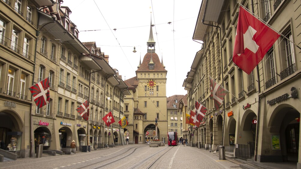 Une rue bordée de voies de tramway, d’immeubles et de drapeaux. 1
